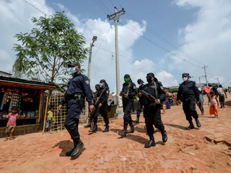 In this photograph taken on October 7, 2020, Rapid Action Battalion (RAB) personnel patrol along a street in Jamtoli refugee camp for Rohingyas in Ukhia. Boatloads of Rohingya landing across Southeast Asia are victims of complex human trafficking networks run by a dizzying web of players, from crime bosses and corrupt cops to poor fishermen, rickshaw drivers and even Rohingya themselves. Munir UZ ZAMAN / AFP