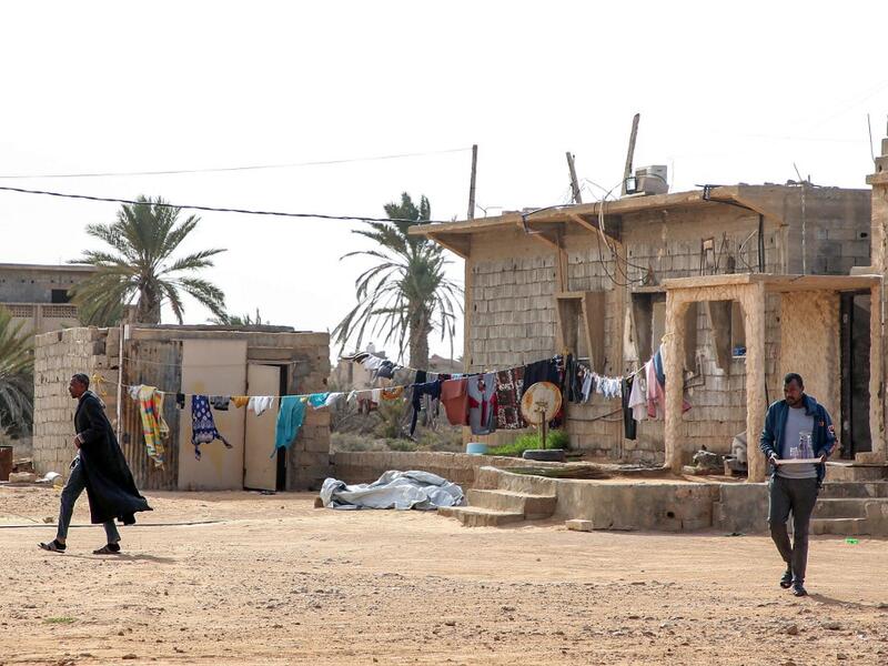 A man walks near a laundry clothing line hanging in the open by a building in the city of Tawergha, some 200 kilometres (125 miles) east of Libya's capital close to the port city of Misrata, on December 12, 2020. When Libyan dictator Moamer Kadhafi was toppled, people took revenge on those they saw as his supporters -- including the entire town of Tawergha, whose 40,000 residents were forced to flee. Now, almost a decade later since militia forces rampaged through the town torching homes, destroying buildin