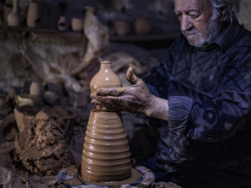 Syrian-Armenian potter Misak Antranik Petros uses an ancient pottery wheel to churn different types of pots at his workshop located inside an ancient mud-brick house near the city of Qamishli in Syria's northeastern Hasakeh province, on December 19, 2020. Petros was only a teenager when he had to take over for his sick father and become the main potter of the family. He has since become a master of the craft, and is keen to pass his skills on.  Delil SOULEIMAN / AFP
