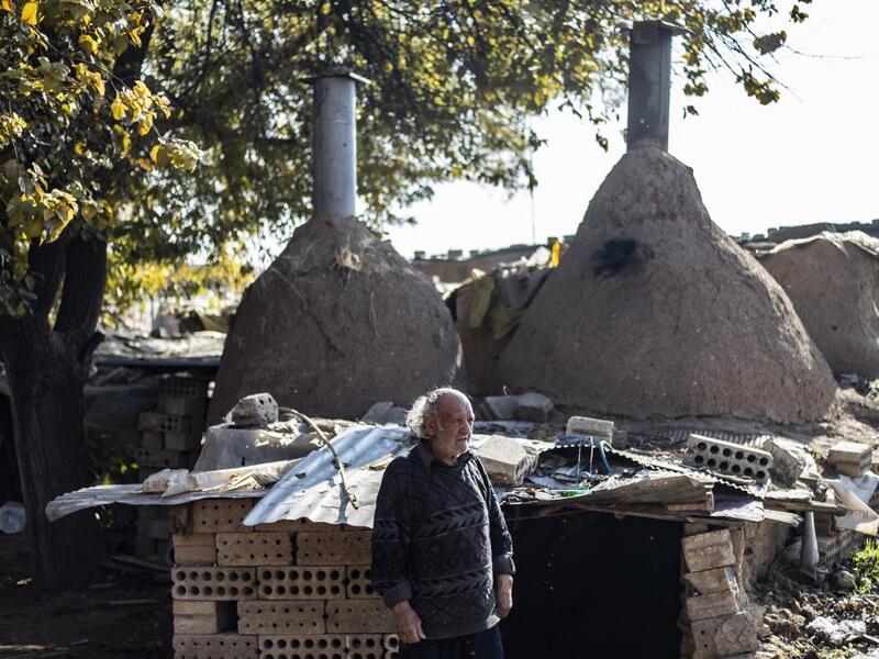 Syrian-Armenian potter Misak Antranik Petros walks outside his workshop located inside an ancient mud-brick house near the city of Qamishli in Syria's northeastern Hasakeh province, on December 19, 2020. Petros was only a teenager when he had to take over for his sick father and become the main potter of the family. He has since become a master of the craft, and is keen to pass his skills on.  Delil SOULEIMAN / AFP