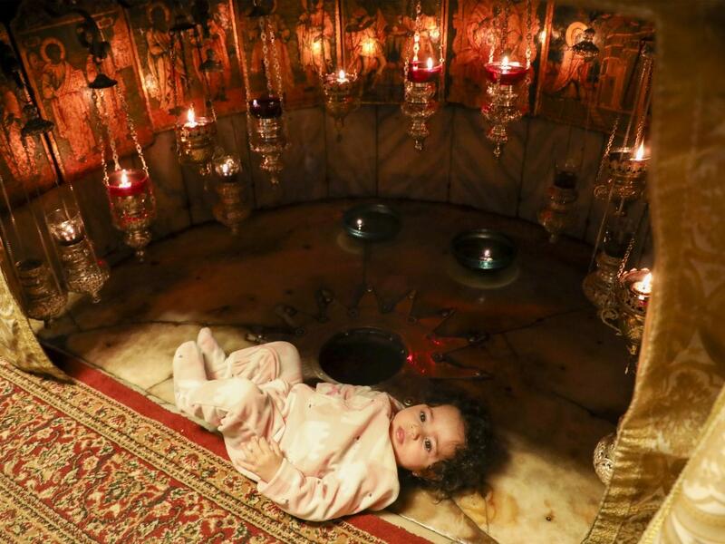A child is pictured near the 14-pointed silver star at the Grotto, believed to be the exact spot where Jesus Christ was born and where Christian worshippers come to pray in the Church of the Nativity, in the West Bank city of Bethlehem, on December 20, 2020. The church was re-opened for prayers following strict COVID-19 restrictions imposed by the Palestinian authorities to curb the spread of the novel coronavirus. HAZEM BADER / AFP