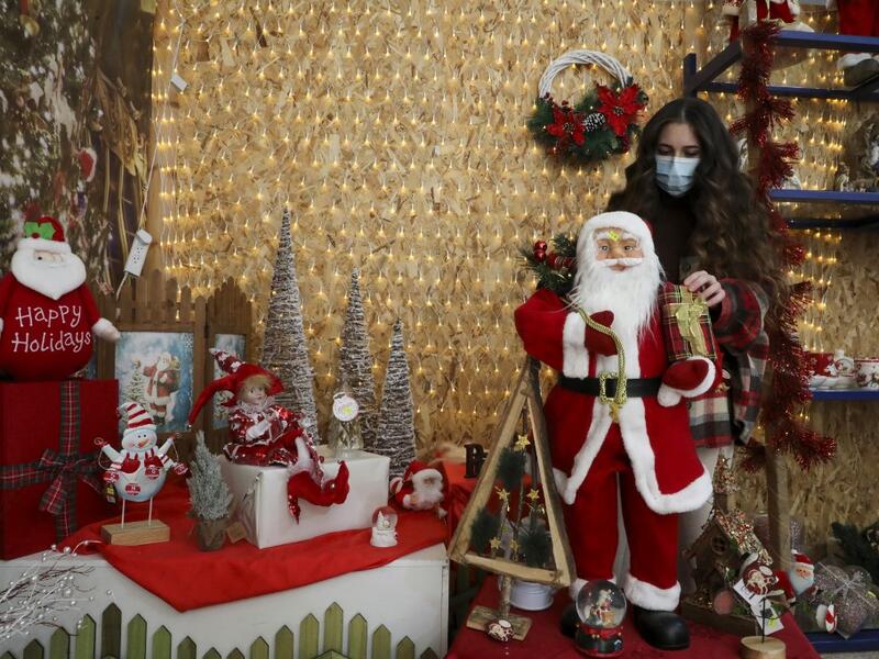 A Palestinian shop-owner arranges Christmas decorations at her shop in the West Bank city of Bethlehem on December 21, 2020. HAZEM BADER / AFP