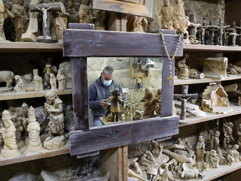 A Palestinian carpenter carves religious statues and figurines from olive wood at a shop near the Church of the Nativity, in the West Bank city of Bethlehem on December 21, 2020. HAZEM BADER / AFP