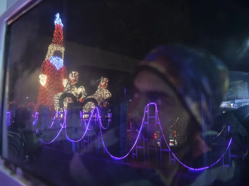 A car driver looks at a model of Santa Claus illuminated, on the eve of Christmas in Siliguri on December 24, 2020. DIPTENDU DUTTA / AFP