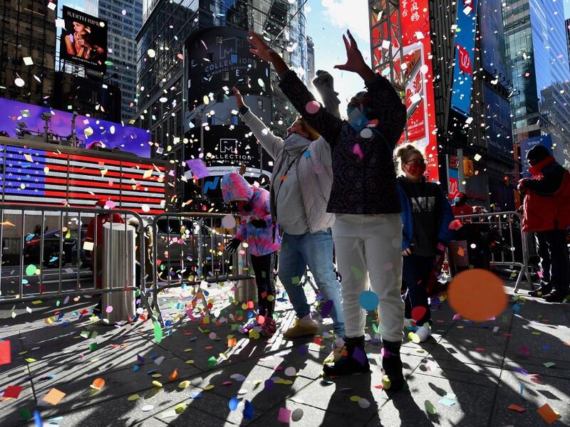 People play with confetti as New Year's Eve organizers test the air worthiness of confetti from the Hard Rock Cafe Marquee in Times Square on December 29, 2020 in New York City. The 2,000 pounds of confetti (907 kilograms) released on New Year’s Eve will include thousands of wishes from individuals who have submitted them at the New Year’s Eve Wishing Wall. Angela Weiss / AFP