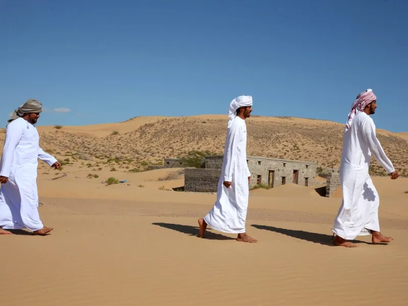 Former inhabitants of Wadi al-Murr, walk near abandoned houses in the Omani village, about 400 kms (250 miles) southwest of the capital Muscat, on December 31, 2020. Encroaching desert sands have left little evidence that Wadi al-Murr ever existed, but former inhabitants, while resigned to its destruction, are trying to preserve its memory. MOHAMMED MAHJOUB / AFP