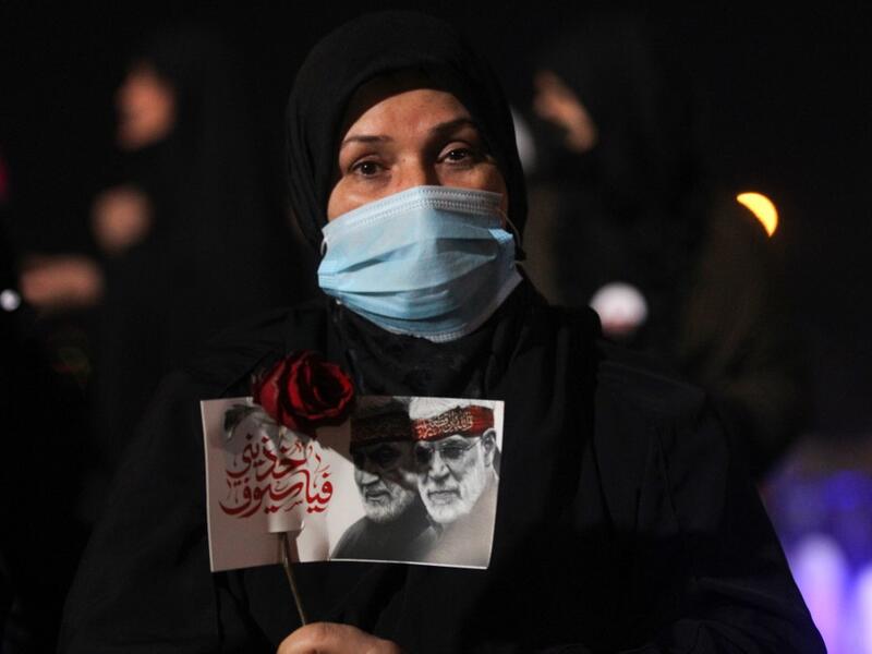 An Iraqi woman carries a portrait of late Iraqi commander Abu Mahdi al-Muhandis and Iranian commander Qasem Soleimani at Baghdad Airport, in Baghdad on January 2, 2021, at the site of their killing. On January 3, 2021, Iraq will mark the first anniversary of the killing of Iran's top military commander Qasem Soleimani in a drone strike at Baghdad International Airport that was authorized by US President Trump. AFP