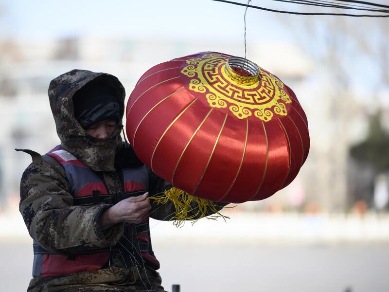 A worker installs a lantern by the icy Lake Houhai in Beijing on January 7, 2021, after China's meteorological authority recently issued a severe weather warning across large parts of the country. NOEL CELIS / AFP