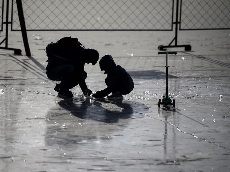 People gather on the frozen Lake Houhai in Beijing on January 7, 2021, after China's meteorological authority recently issued a severe weather warning across large parts of the country. NOEL CELIS / AFP