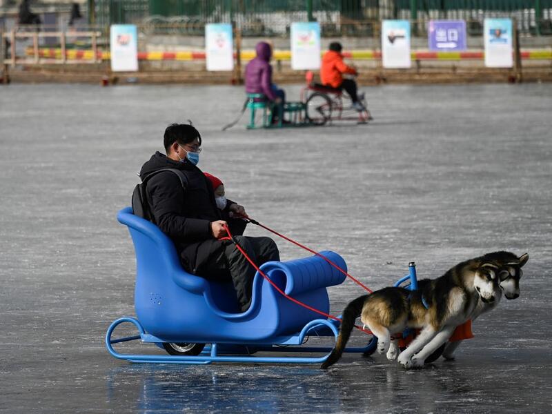 A man and a child use a sled on a frozen lake in Beijing on January 12, 2021. WANG Zhao / AFP