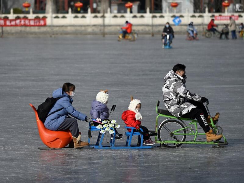 A family uses a sled on a frozen lake in Beijing on January 12, 2021. WANG Zhao / AFP
