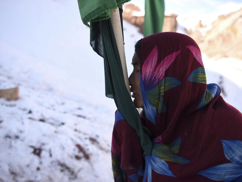 In this photo taken on January 6, 2021, a Hazara woman Jawahir Sedaqat, who lost two sons in an explosions on November 24 last year in the city of Bamiyan, prays and kisses a flag at a graveyard of her sons in Somarah village on the outskirts of Bamiyan province. Comprising roughly 10 to 20 percent of Afghanistan's 38-million population, Hazaras have long been persecuted for their largely Shiite faith by Sunni hardliners in a country wracked by deep ethnic divisions. WAKIL KOHSAR / AFP