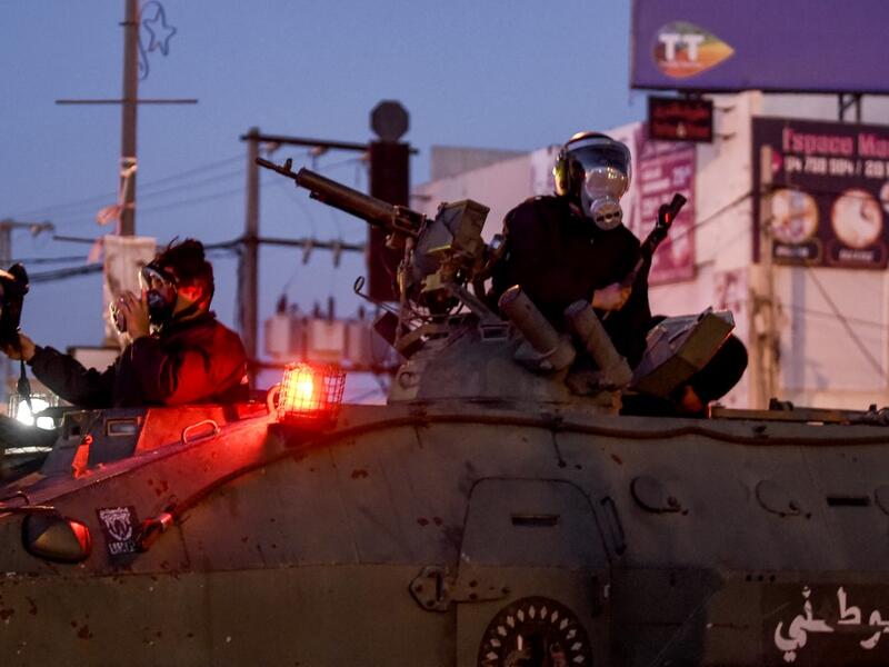 Members of Tunisia's National Guard sit atop an armoured personnel carrier preparing for clashes with protesters in the Ettadhamen city suburb on the northwestwern outskirts of Tunisia's capital Tunis on January 17, 2021, amidst a wave of nightly protests in the North African country. FETHI BELAID / AFP