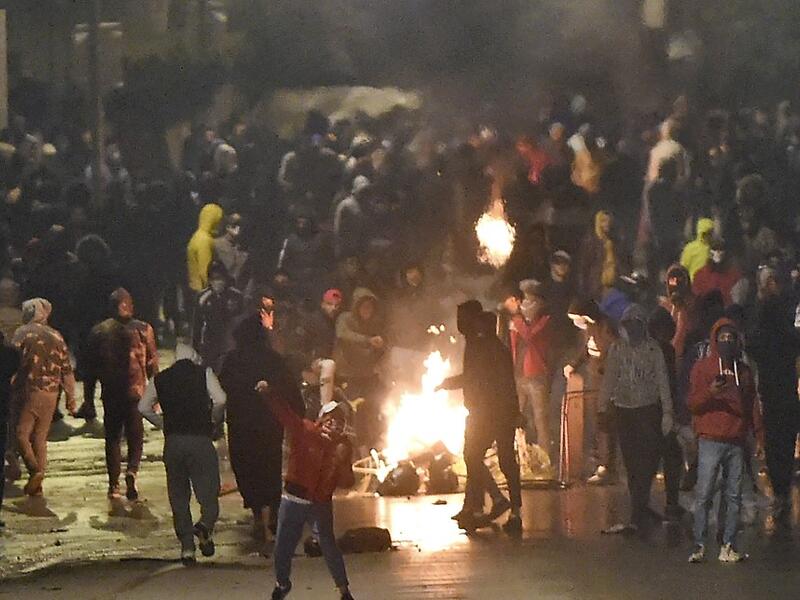 Tunisian protesters block a street during clashes with security forces in the Ettadhamen city suburb on the northwestwern outskirts of Tunis on January 18, 2021, amidst a wave of nightly protests in the North African country. The social unrest comes at a time of economic crisis, worsened by the pandemic, that has sparked rapid inflation and high youth unemployment and led many people to leave Tunisia. FETHI BELAID / AFP