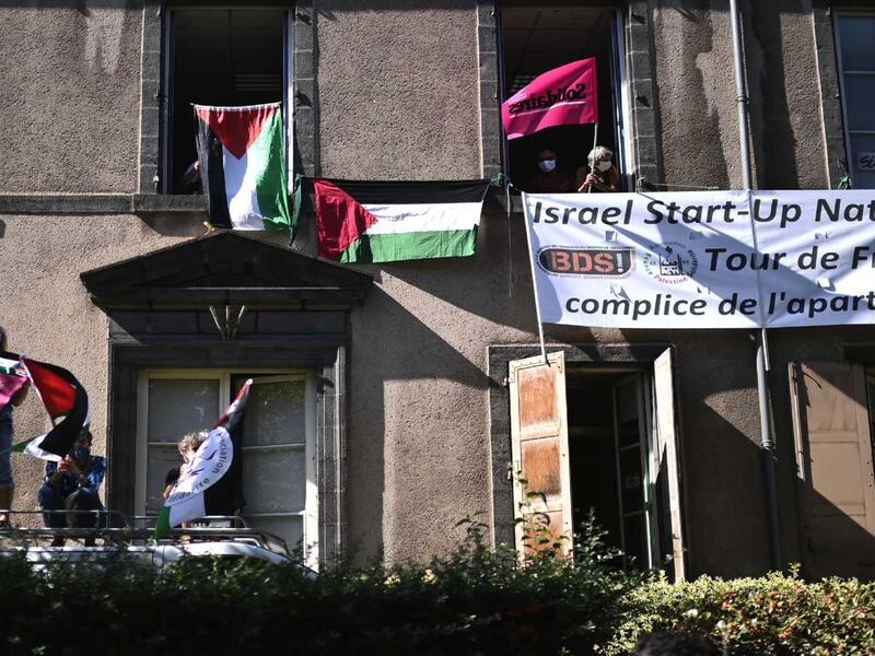 Boycott, Divestment, Sanctions (BDS) movement activists display Palestinian flags and a banner reading "Israel Start-Up Nation, Tour de France is the accomplice of the apartheid" as the pack rides during the 13th stage of the 107th edition of the Tour de France cycling race, 191 kilometers between Chatel-Guyon and Puy Mary, on Sept. 11, 2020. Photo by MARCO BERTORELLO/AFP via Getty Images