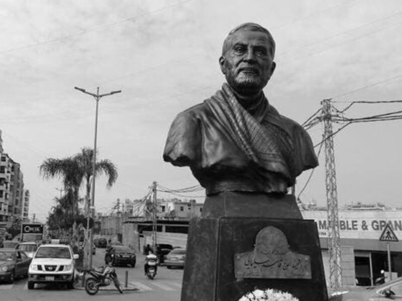 A photo taken on January 5, 2021 shows a Lebanese flag hanging on a building under construction behind the newly unveiled statue of Iran's most revered military commander, Qasem Soleimani, in the predominantly-Shiite Muslim Beirut southern suburb of Ghobeiry. Soleimani -- whom the US blamed for attacks on its interests in Iraq and elsewhere -- was killed in a US drone strike at Baghdad airport on January 3 last year, ratcheting up tensions between decades-old arch foes the United States and Iran. JOSEPH EID