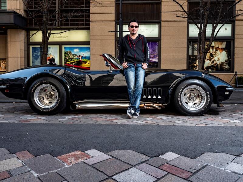 This picture taken on January 16, 2021 shows real estate and construction business owner Atsushi Hasegawa posing for a photo with a 1969 Chevrolet Corvette during a gathering of auto enthusiasts in Tokyo. A loose club of fans rolls up most weekends in central Tokyo to show off their Cadillacs, Chevrolets and other modern classic vehicles from the mid to late 20th century. Philip FONG / AFP