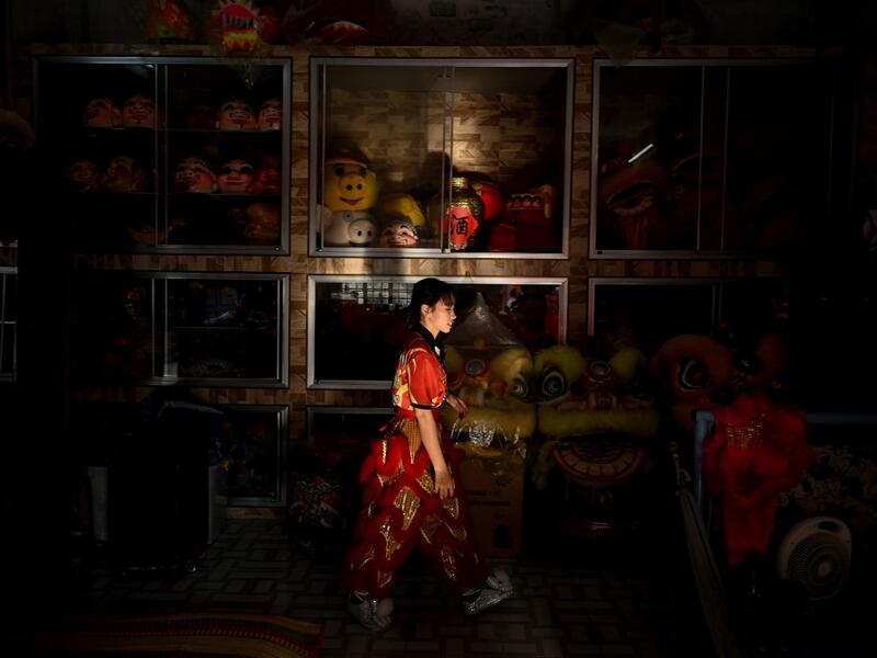 This photograph taken on January 20, 2021 shows Huynh Thi Kim Dieu walking past a room full of costumes before practice at the Tu Anh Duong lion and dragon dance school in Can Tho city in southern Vietnam's Mekong Delta. Manan VATSYAYANA / AFP