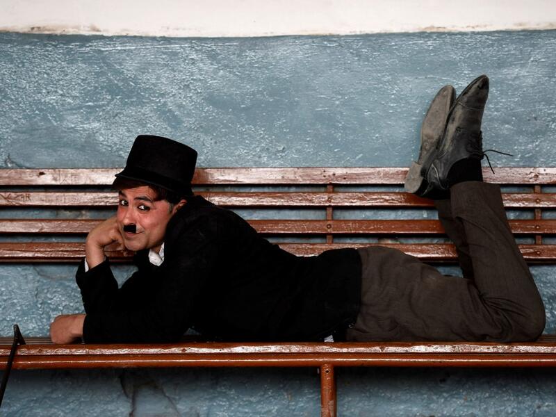 In this picture taken on February 9, 2021, street actor Usman Khan, dressed up as silent film star Charlie Chaplin, performs at a train station in the Pakistan's northwestern city of Peshawar. Wearing a bowler hat and familiar toothbrush moustache, Pakistan's Usman Khan darts through traffic swinging a cane, teasing motorists and shopkeepers for laughs and a few rupees with a Charlie Chaplin impersonation that has become a viral sensation.  Abdul MAJEED / AFP