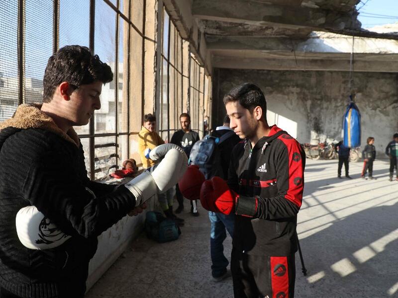 Syrian youths take part in a boxing workout held by local boxer Ahmad Dwara (unseen) inside a damaged building in the town of Atareb in the rebel-held western countryside of Syria's Aleppo province, on February 11, 2021. AAREF WATAD / AFP