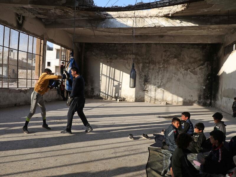 Displaced Syrian boxer Ahmad Dwara trains youth inside a damaged building in the town of Atareb in the rebel-held western countryside of Syria's Aleppo province, on February 11, 2021. AAREF WATAD / AFP