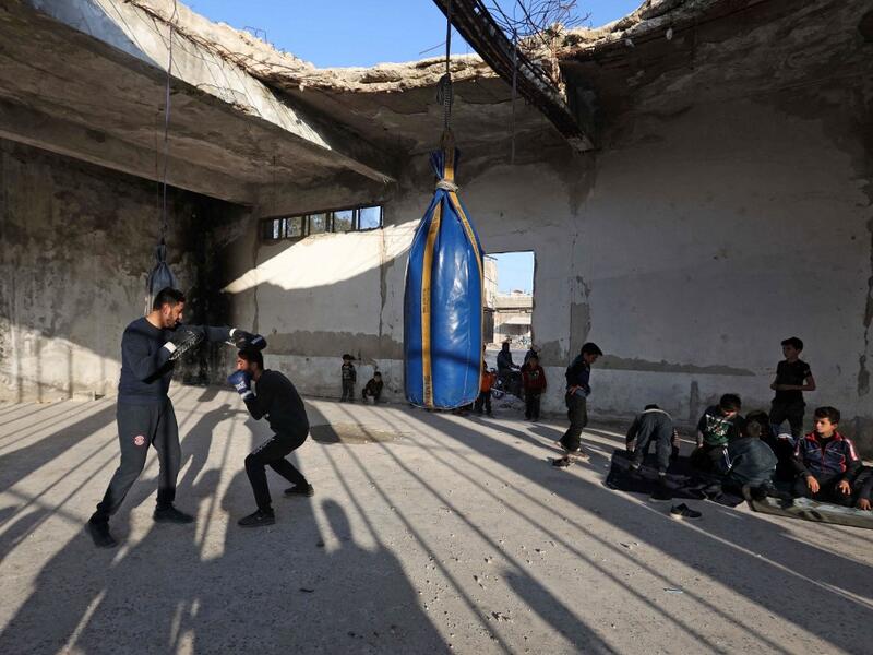 Displaced Syrian boxer Ahmad Dwara trains youth inside a damaged building in the town of Atareb in the rebel-held western countryside of Syria's Aleppo province, on February 11, 2021. AAREF WATAD / AFP
