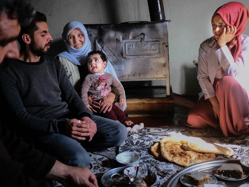 In this photograph taken on February 15, 2021, nurse Yildiz Ayten (R) from Bahcesaray public hospital vaccination team, enjoys her lunch offered by Kurdish inhabitant Zeri Saymaz (2nd-L) and her family after receiving her vaccine, at the village of Guneyyamac in eastern Turkey, as part of an expedition to vaccinate residents of 65 years old or above with Sinovac's CoronaVac Covid-19 vaccine. Turkey's population of more than 83 million is spread out across Europe and Asia and covers some seemingly impregnabl
