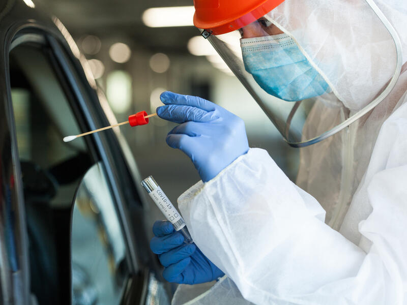 Medical NHS worker in personal protective equipment swabbing a person in a car drive through Coronavirus COVID-19 mobile testing center. (Shutterstock/ File Photo)