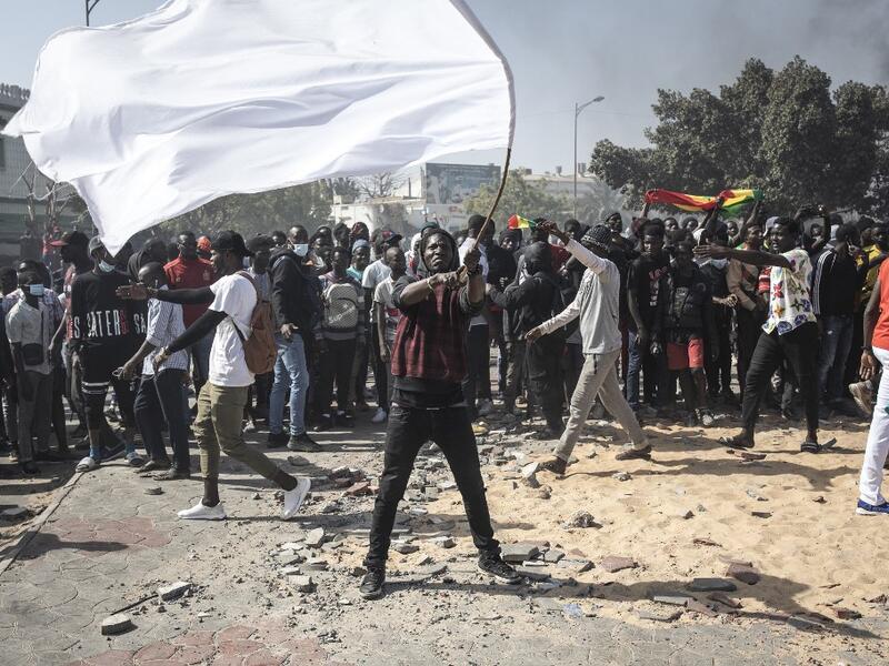 A protester waves a white flag during a protest in Dakar on March 8, 2021, after the country's opposition leader Ousmane Sonko was charged with rape. Usually considered a beacon of stability in a volatile region, deadly clashes between opposition supporters and security forces have rocked the West African state. JOHN WESSELS / AFP