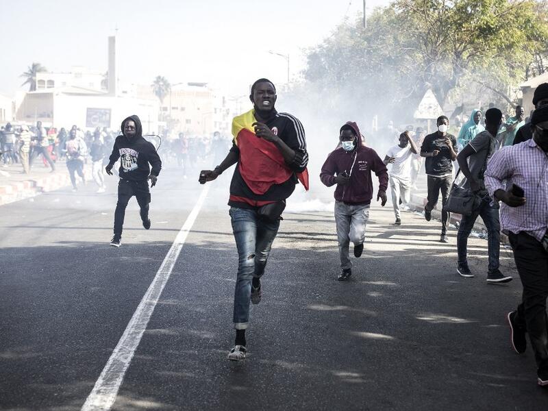 Protesters run from teargas during a protest in Dakar on March 8, 2021, after the country's opposition leader Ousmane Sonko was charged with rape. Usually considered a beacon of stability in a volatile region, deadly clashes between opposition supporters and security forces have rocked the West African state. JOHN WESSELS / AFP