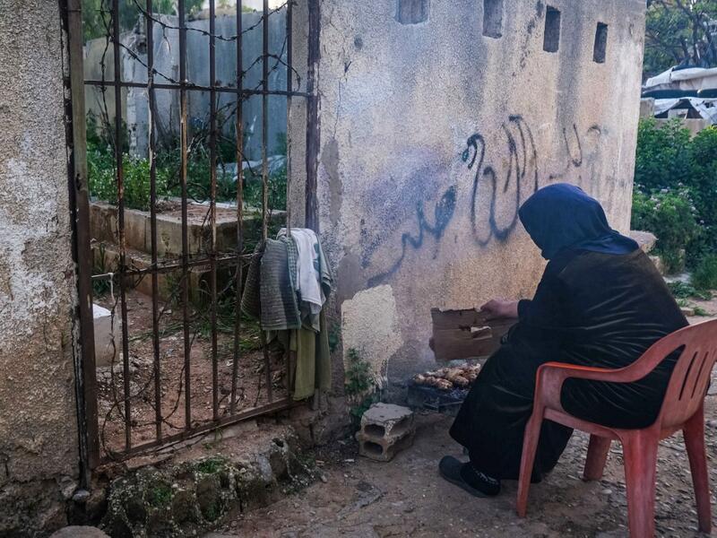 A woman grills chicken near a grave, as she prepares the fast-breaking "Iftar" meal