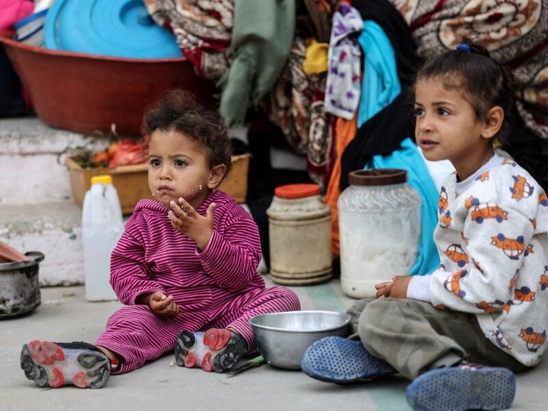 Palestinan children eat as families took shelter at a United Nations (UN) school in Rafah in the southern Gaza Strip on May 17, 2021. Israeli air strikes hammered the Hamas-controlled territory after a week of violence which has killed more than 200 people, the large majority Palestinian, despite international calls for de-escalation