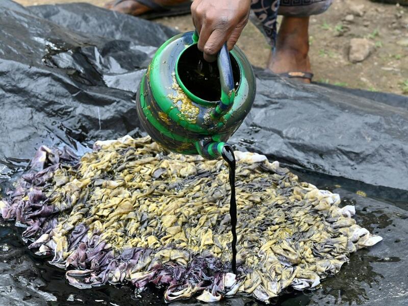 Dyers dye cotton fabric at Pathe'O house in the popular district of Treichville in Abidjan on March 31, 2021. A small self-taught tailor in his early years, the Ivorian-Burkinabe Pathe'O became the designer of African heads of state and celebrates the fiftieth anniversary of his brand, leading the "fight" for the recognition of fashion on the continent