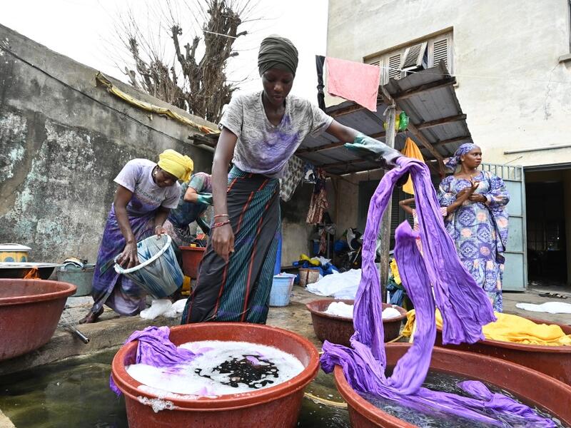 Dyers dye cotton fabric at Pathe'O house in the popular district of Treichville in Abidjan on March 31, 2021. A small self-taught tailor in his early years, the Ivorian-Burkinabe Pathe'O became the designer of African heads of state and celebrates the fiftieth anniversary of his brand, leading the "fight" for the recognition of fashion on the continent. 
