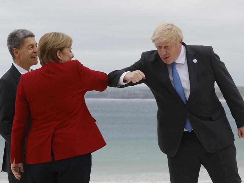 Britain's Prime Minister Boris Johnson (R) elbow-bumps Germany's Chancellor Angela Merkel as he greets her and her husband Joachim Sauer at the G7 summit in Carbis Bay, Cornwall on June 11, 2021. G7 leaders from Canada, France, Germany, Italy, Japan, the UK and the United States meet this weekend for the first time in nearly two years, for three-day talks in Carbis Bay, Cornwall