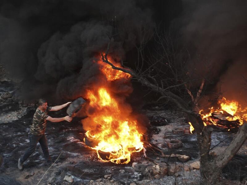 A Palestinian man sets a tire on fire in the village of Beita, south of Nablus, in the occupied West Bank, across the valley from the newly built Israeli settlers' outpost of Eviatar, on June 13, 2021. With flashing lasers, honking horns and choking smoke from burning tires, the latest tactics used by Palestinian protesters are dusk till dawn rallies to make life unbearable for Israeli settlers