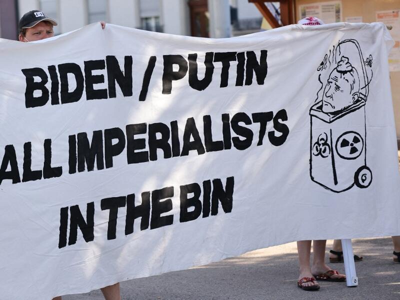 Protesters holds a banner against US and Russian Presidents during the US-Russia summit at the Villa La Grange