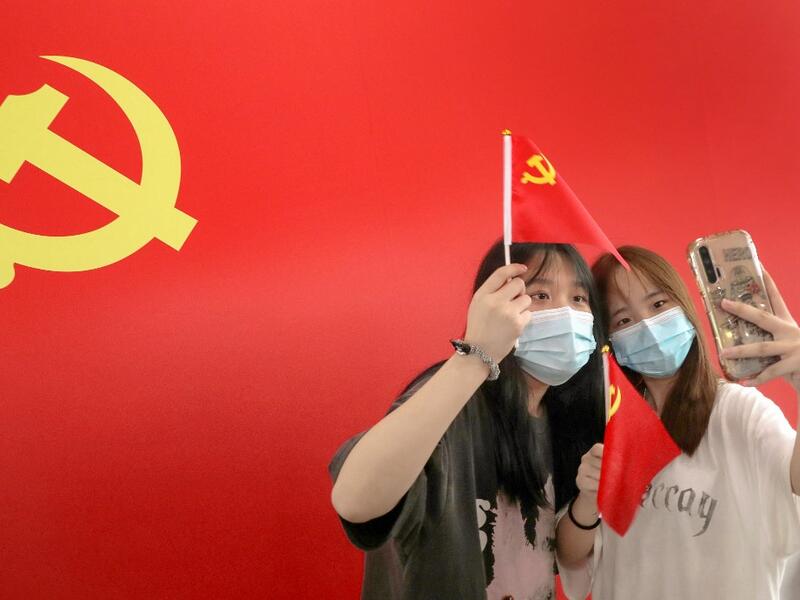 Passengers take photos with a flag of the Communist Party of China at the Nantong Railway Station in China's eastern Jiangsu province on July 1, 2021, during celebrations to mark the 100th anniversary of the founding of the Communist Party of China