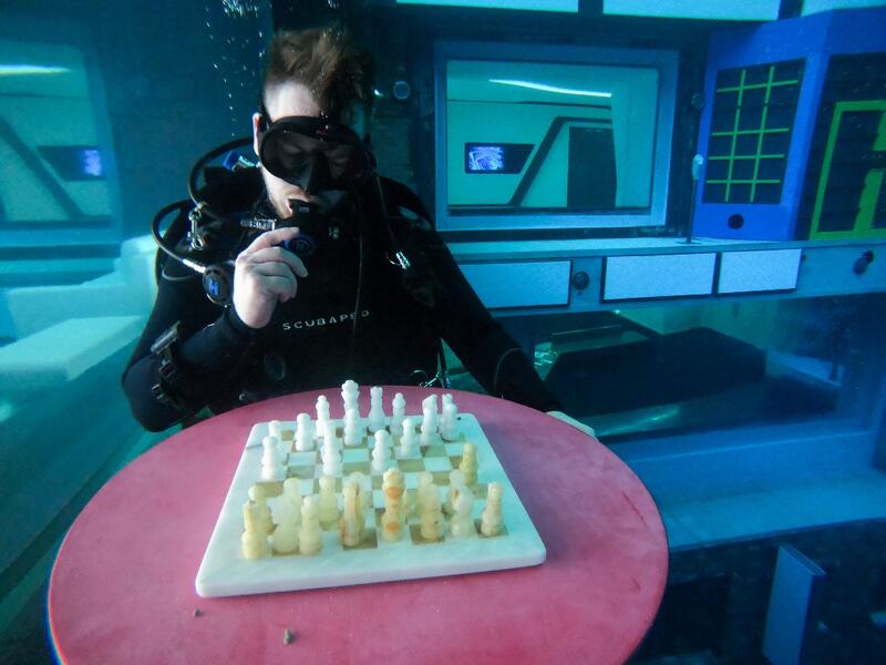 A diver plays mock chess as he experiences Deep Dive Dubai, the deepest swimming pool in the world reaching 60m, in the United Arab Emirates, on July 10, 2021. The city of superlatives, with the world's tallest tower among its many records, Dubai now has the deepest swimming pool on the planet complete with a "sunken city" for divers to explore. GIUSEPPE CACACE / AFP