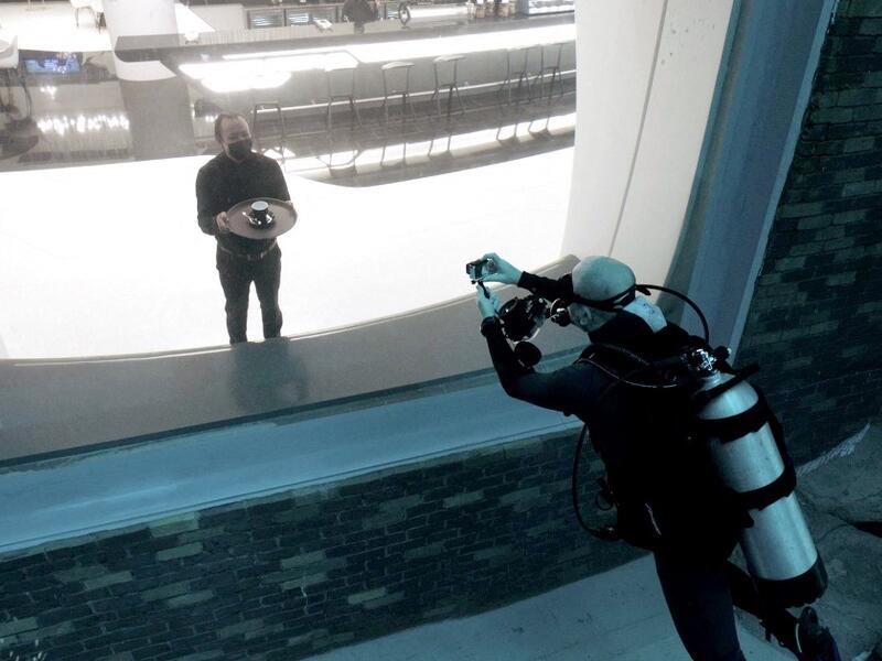A diver experiencing Deep Dive Dubai, the deepest swimming pool in the world reaching 60m, photographs a waiter through a viewing glass, on July 10, 2021. The city of superlatives, with the world's tallest tower among its many records, Dubai now has the deepest swimming pool on the planet complete with a "sunken city" for divers to explore. GIUSEPPE CACACE / AFP