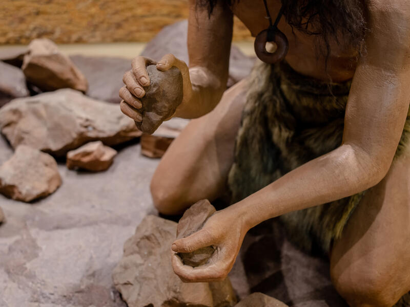 man set on fire with fire stone for cooking in stone age
