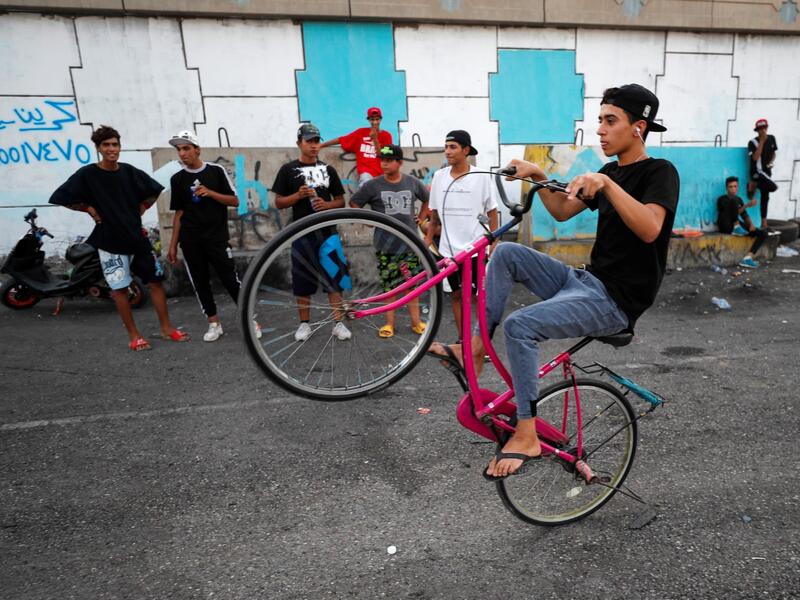 An Iraqi youth performs stunts on a bicycle in the Jadriya district of Baghdad on August 6, 2021. All dressed up and nowhere to go: many young Iraqis in Baghdad make an effort to be hip, even as they admit their country may have no future.