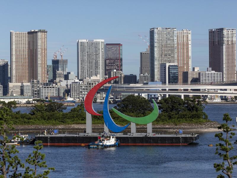 The Paralympic Symbol "the three agitos", 23.4m wide and 17.5m high, is brought by a salvage barge to install at the Tokyo waterfront in the waters of Odaiba Marine Park on August 20, 2021, four days before the opening of the Tokyo 2020 Paralympic Games. 