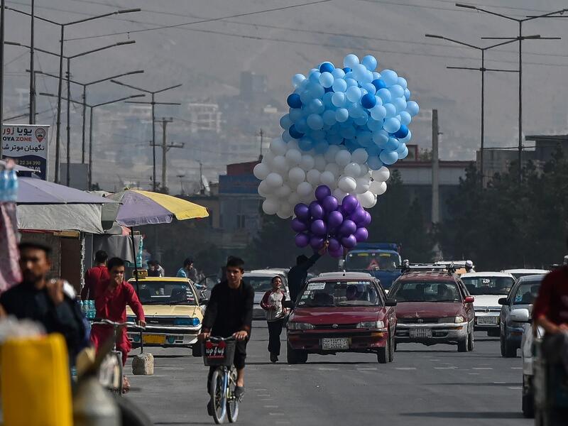 An Afghan man selling balloons rides in a car in Kabul on September 21, 2021. 