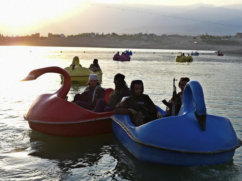 In this photograph taken on September 28, 2021 Taliban fighters ride on paddle boats at Qargha Lake on the outskirts of Kabul. "This is Afghanistan!" a Taliban fighter shouts on the pirate ship ride at a fairground in western Kabul, as his armed comrades cackle and whoop on board the rickety attraction. (Photo by WAKIL KOHSAR / AFP) / TO GO WITH: AFGHANISTAN-CONFLICT-FAIRGROUND, SCENE BY JAMES EDGAR - TO GO WITH: Afghanistan-conflict-fairground, SCENE by James EDGAR