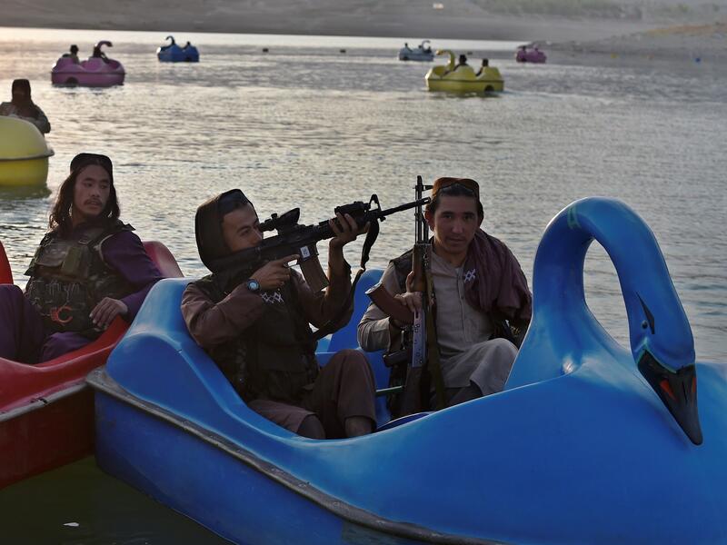 In this photograph taken on September 28, 2021 Taliban fighters ride on paddle boats at Qargha Lake on the outskirts of Kabul. "This is Afghanistan!" a Taliban fighter shouts on the pirate ship ride at a fairground in western Kabul, as his armed comrades cackle and whoop on board the rickety attraction. (Photo by WAKIL KOHSAR / AFP) / TO GO WITH: AFGHANISTAN-CONFLICT-FAIRGROUND, SCENE BY JAMES EDGAR - TO GO WITH: Afghanistan-conflict-fairground, SCENE by James EDGAR