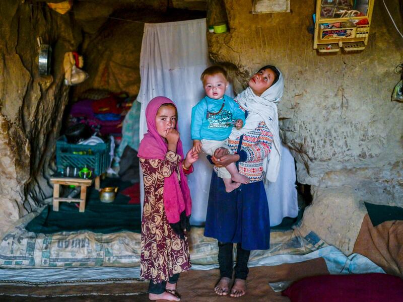 In this picture taken on October 3, 2021, Hazara ethnic children stand in their cave on a cliff pockmarked by caves where people still live as they did centuries ago in Bamiyan. 