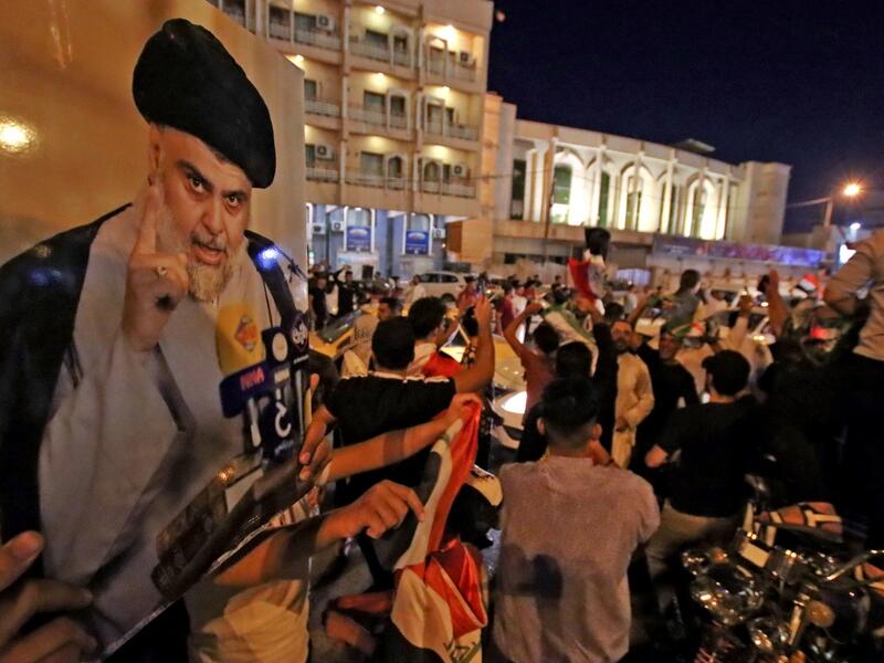 Supporters of Iraqi Shiite cleric Muqtada al-Sadr ride in vehicles while celebrating in the central shrine city of Najaf after the closure of polls during the early parliamentary elections on October 10, 2021. (Photo by Ali NAJAFI / AFP)