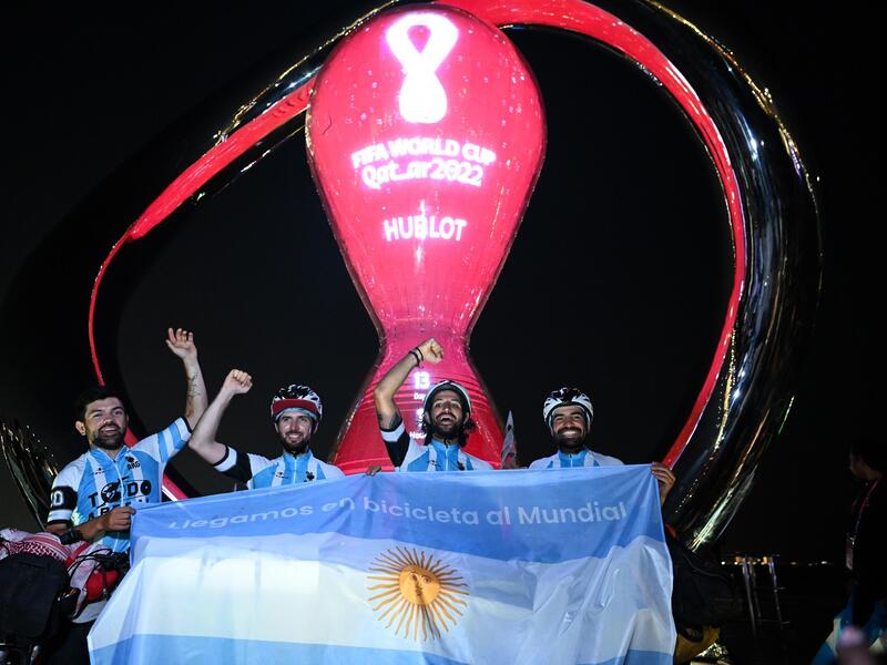 (L-R) Argentina's cyclists Matias Villarroel, Silvio Gatti, Leandro Blanco, and Lucas Ledezma pose for photos in front of the FIFA World Cup countdown clock upon arriving in Doha on November 7, 2022, ahead of the Qatar 2022 FIFA World Cup football tournament. (Photo by Kirill KUDRYAVTSEV / AFP)