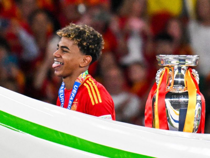 Spain's forward #19 Lamine Yamal reacts next to the trophy after winning the UEFA Euro 2024 final football match between Spain and England at the Olympiastadion in Berlin on July 14, 2024. (Photo by Jewel SAMAD / AFP)